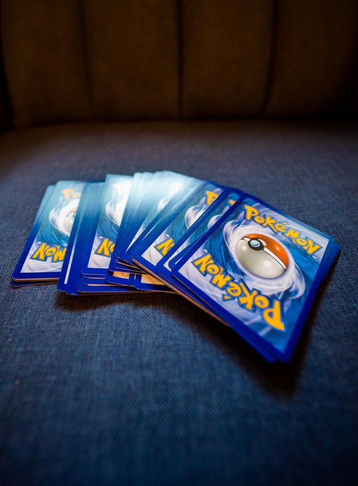Mastering the First Impression: Your intriguing post title goes here A collection of Pokemon trading cards arranged on a blue couch, ideal for collectors and fans.