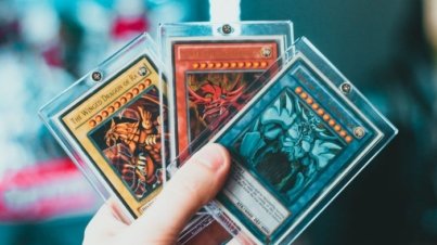 Close-up of a hand holding collectible trading cards in protective cases.